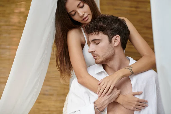Romantisches Paar, tätowierte Frau mit geschlossenen Augen, die Mann umarmt und im privaten Pavillon sitzt — Stockfoto
