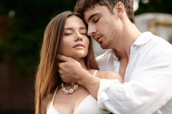 Porträt eines gutaussehenden Mannes, der Freundin in bauchfreiem Top umarmt und zusammen im Freien steht, Romantik — Stockfoto
