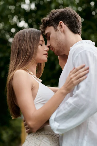 Vue latérale de bel homme embrassant petite amie dans le haut de la culture et debout ensemble à l'extérieur, romance — Photo de stock