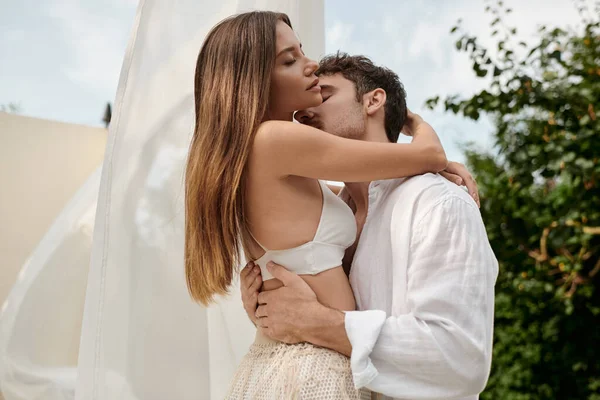 Leidenschaftliches Paar, Mann verführt sexy Frau, während er neben weißem Tüll des Pavillons am Strand steht — Stockfoto