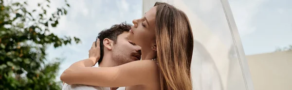 Sexy pareja, hombre besos cuello de mujer mientras que de pie cerca de blanco tul de pabellón en la playa, bandera - foto de stock