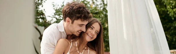 Joyful couple, happy man hugging cheerful woman while standing together near white tulle, banner — Stock Photo