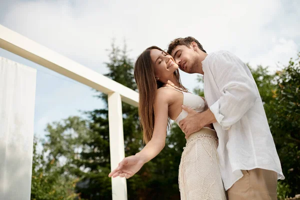 Leidenschaftlicher Mann umarmt fröhliche Frau in weißer Strandkleidung auf Luxus-Resort im Urlaub — Stockfoto