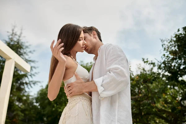 Leidenschaftlicher Mann umarmt hübsche Frau in weißer Strandkleidung auf Luxus-Resort im Urlaub — Stockfoto