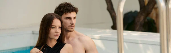 Hemdloser Mann und hübsche Frau in Badebekleidung stehen zusammen am Pool, Paar im Resort, Banner — Stockfoto