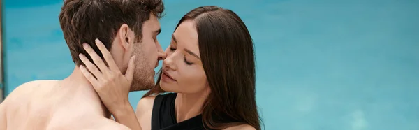 Mulher de maiô preto abraçando e beijando homem sem camisa na piscina, casal sexy em férias, banner — Fotografia de Stock