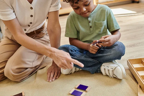 Montessori conceito de caixa de cor, professor apontando perto de menino americano africano inteligente, jogo educativo — Fotografia de Stock