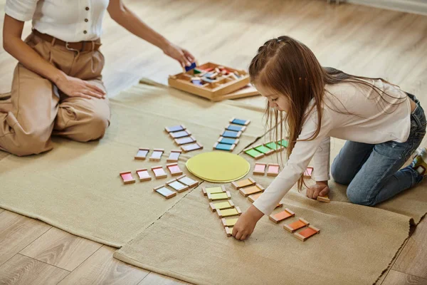 Школа Монтессорі, дівчина біля кольорової освітньої гри у формі сонця, вчителька, освіта — стокове фото