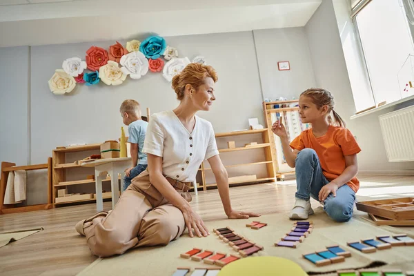 Jeu de correspondance des couleurs, fille montrant un morceau de matériel montessori à une enseignante heureuse, éducatif — Photo de stock