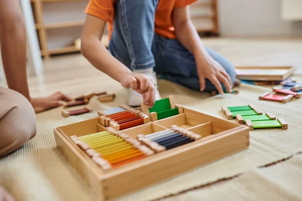 Concept de l'école montessori, vue recadrée de fille jouant jeu de correspondance des couleurs près de l'enseignant, jeu basé sur — Photo de stock