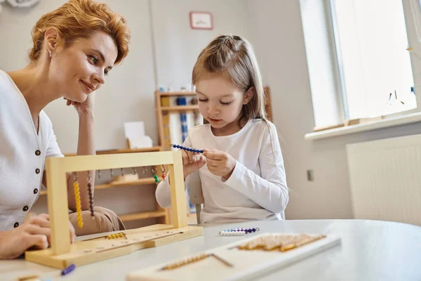 Montessori-Konzept, Mädchen spielen mit Farbperlentreppen in der Nähe des Lehrers, Holzständer, pädagogische — Stockfoto