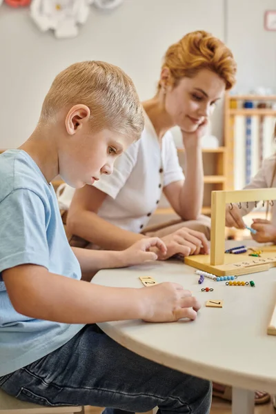 Montessori school, kids playing educational game, math learning, boy counting while looking at tiles — Stock Photo