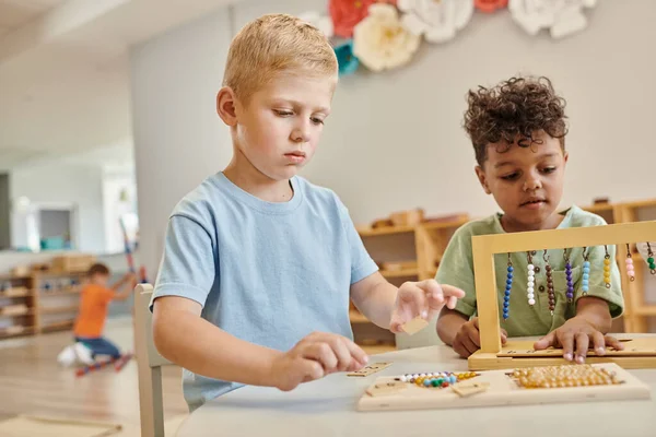 Montessori school concept, multicultural boys playing with color bead stairs, learn through play — Stock Photo