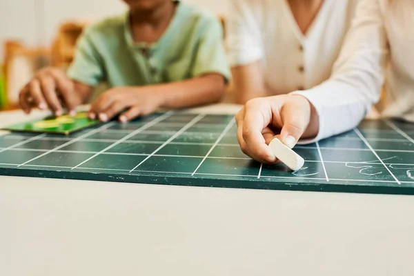 Montessori-Konzept, multikulturelle Kinder, Mädchen schreiben auf Kreidetafel neben Lehrer und afrikanischem Jungen — Stockfoto