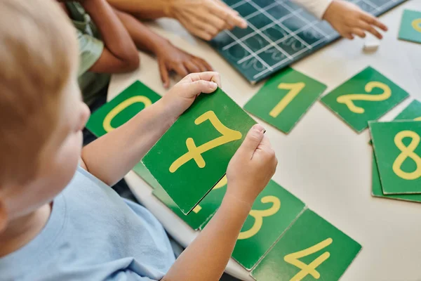 Top view of boy holding number seven card, learning how to count in Montessori school, study — Stock Photo