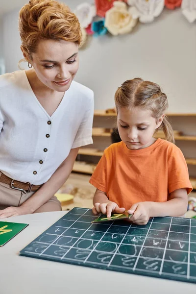 Kluges Mädchen zeigt auf Zahl neben Lehrer, zählt Tafel, lernt spielerisch, Montessori — Stockfoto