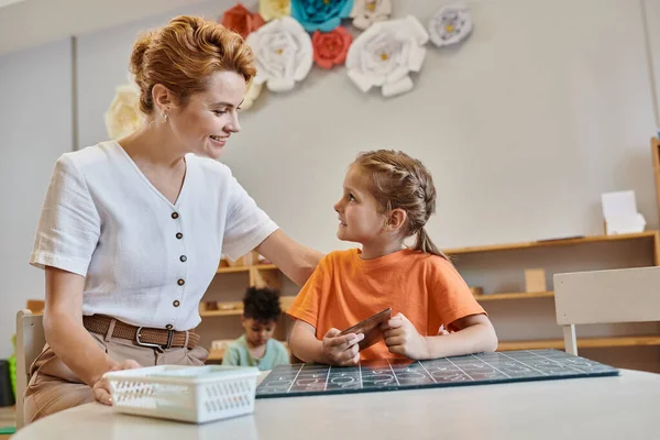 Insegnante felice incoraggiare ragazza intelligente nella scuola Montessori, imparare attraverso il gioco, contare, matematica — Foto stock