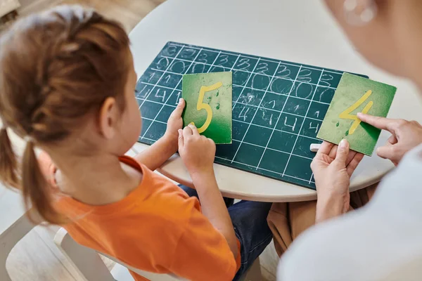 Cleveres Mädchen und Lehrer zeigen auf Zahlen in der Nähe der Tafel, Lernen durch Spielen, Zählen, Ernten — Stockfoto