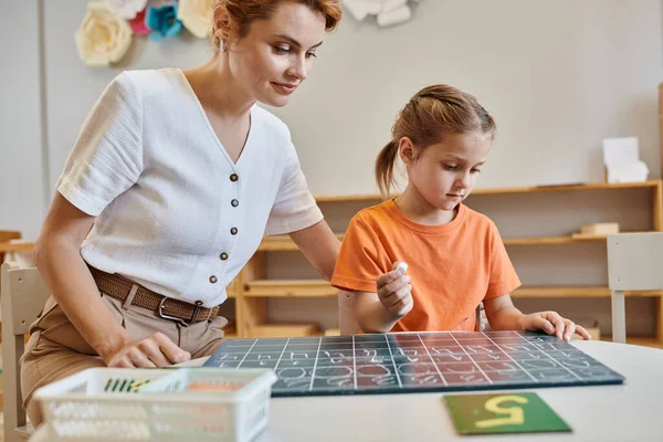 Cleveres Mädchen, das auf der Tafel schreibt, spielerisches Lernen, Mathe, Lehrer, Montessori-Schule — Stockfoto