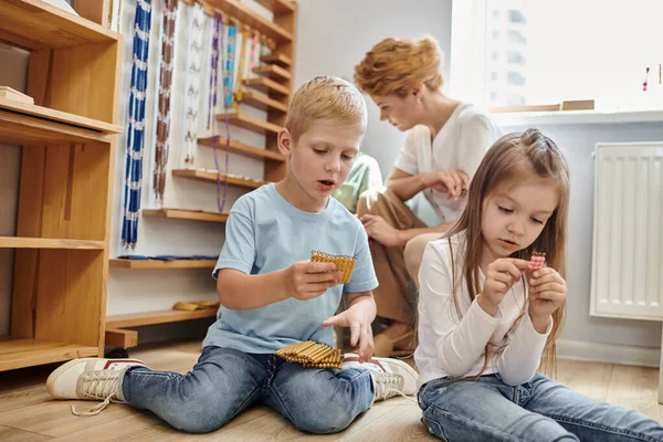 Ragazza e ragazzo in possesso di materiale perline Montessori, conteggio, apprendimento attraverso il gioco, bambini e insegnante — Foto stock