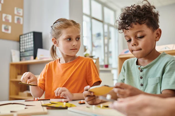 Niños interracial jugando con material didáctico montessori en la escuela, aprender a través del juego, diversión - foto de stock