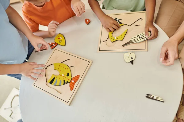 Von oben, beschnittene interrassische Kinder, die in der Schule mit didaktischem Montessori-Material spielen, Puzzle — Stock Photo