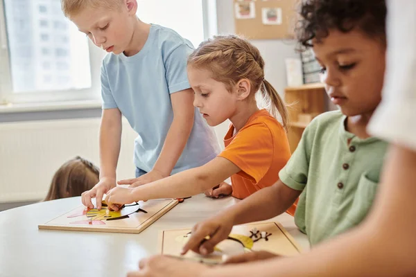 Crianças inter-raciais brincando com materiais didáticos na mesa na escola montessori — Fotografia de Stock