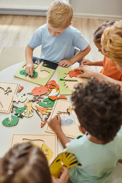 Overhead-Ansicht multiethnischer Kinder und Lehrer mit didaktischen Materialien in der Montessori-Schule — Stockfoto
