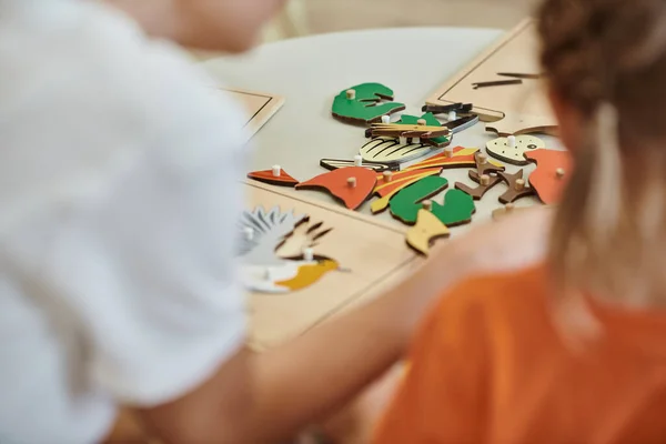 Ausgeschnittene Ansicht didaktischer Materialien auf dem Tisch in der Nähe verschwommener Kinder in der Montessori-Schule — Stockfoto