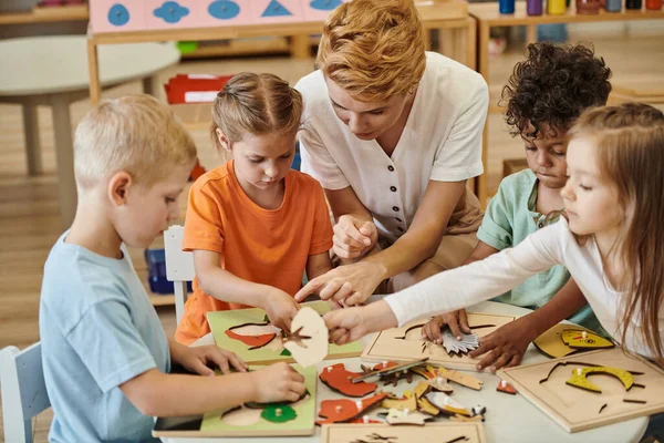 Lehrer spielt in Montessori-Schule mit interrassischen Kindern mit didaktischen Materialien — Stockfoto