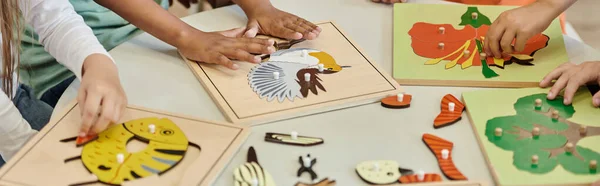 Частичный взгляд детей, играющих с дидактическими материалами во время урока в школе Монтессори, баннер — стоковое фото
