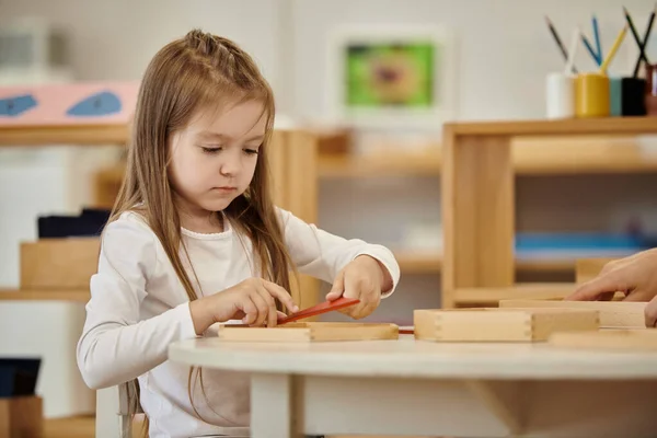 Menina brincando com materiais didáticos de madeira perto de amigo em classe na escola montessori — Fotografia de Stock