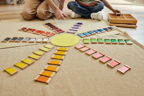 Vista cortada de tijolos coloridos perto de menino afro-americano borrado e professor na escola montessori — Fotografia de Stock