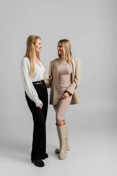 Zwei hübsche blonde Schwestern in formeller Kleidung, die einander lächelnd anschauen, Modekonzept — Stockfoto