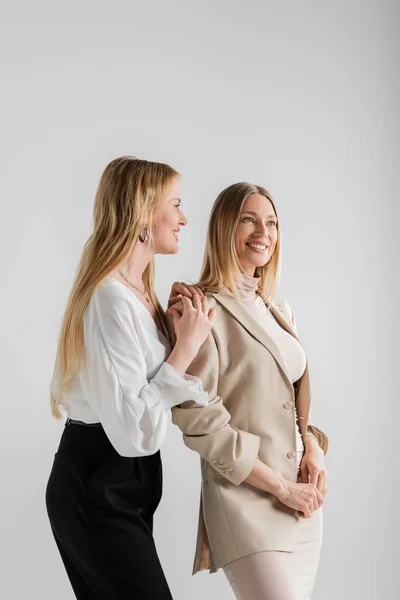 Deux jolies soeurs blondes souriantes et posant sur fond gris, concept de mode — Photo de stock