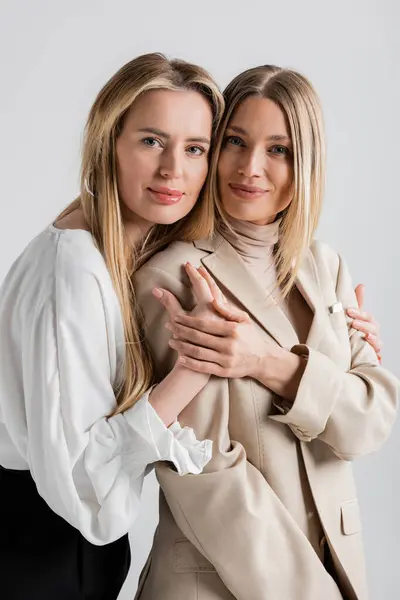 Retrato de dos hermanas lindas con estilo abrazándose y mirando a la cámara, concepto de moda - foto de stock