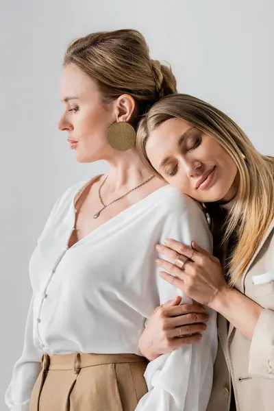 Portrait of voguish sisters in formal pastel attire hugging each other, head on shoulder, fashion — Stock Photo