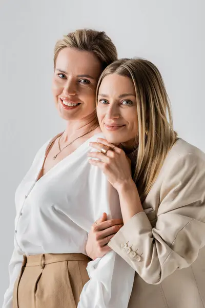 Retrato de alegres irmãs elegantes em traje pastel abraçando e sorrindo, cabeça no ombro, moda — Fotografia de Stock