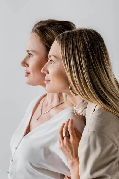 Portrait of stylish sisters in formal pastel attire looking away and hugging, style and fashion — Stock Photo