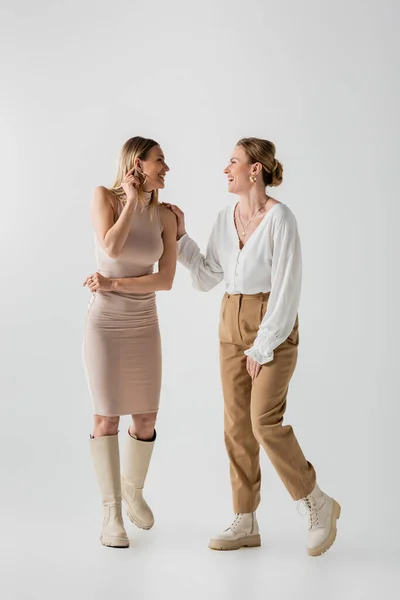 Two trendy stylish blonde sisters in pastel outfits smiling at each other, style and fashion — Stock Photo