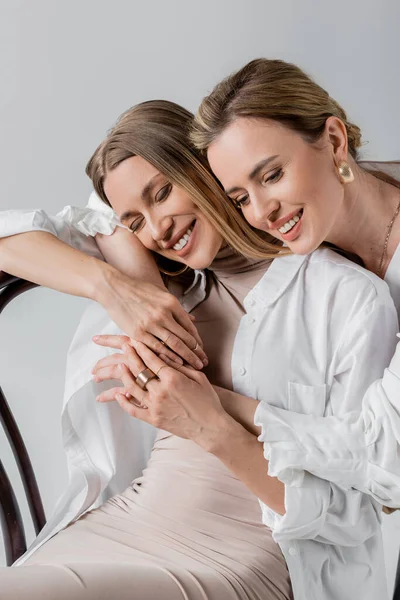 Retrato de hermanas cariñosas con estilo abrazando y sonriendo con los ojos cerrados, estilo y moda - foto de stock