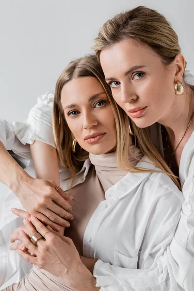 Ritratto di sorelle amorevoli alla moda in abiti pastello che abbracciano e guardano fotocamera, stile e moda — Foto stock