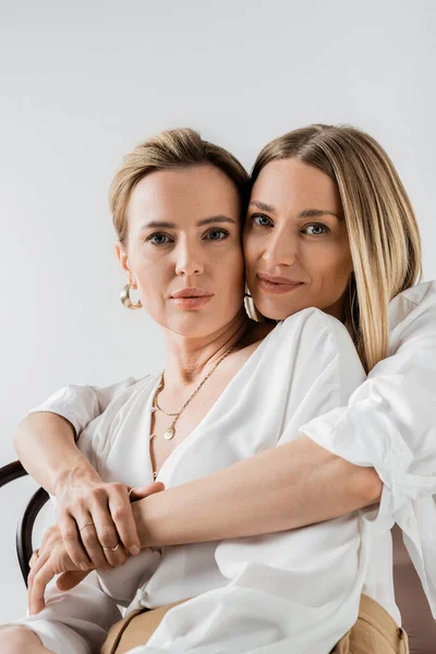 Portrait of two stylish blonde sisters in elegant pastel attire looking at camera, style and fashion — Stock Photo