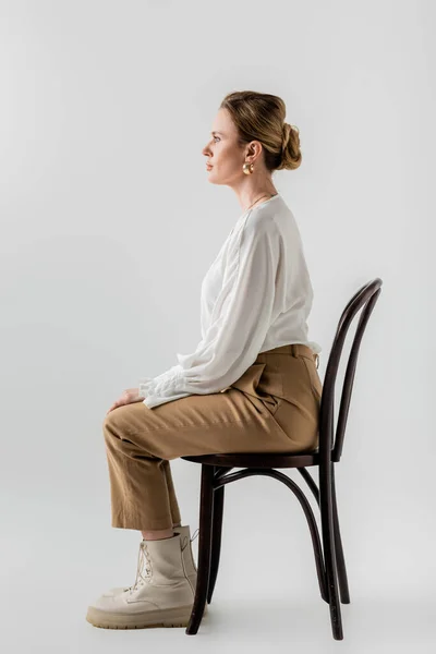 Elegante giovane donna seduta sulla sedia indossa abbigliamento formale alla moda pastello, stile e moda — Foto stock