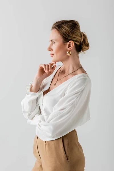Atractiva mujer elegante de pie con los brazos cruzados tocando su barbilla y mirando hacia otro lado, la moda - foto de stock