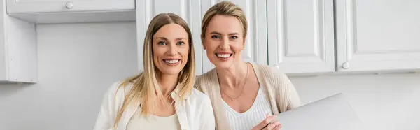 Dos hermanas rubias atractivas sonriendo sinceramente y mirando a la cámara, vinculación familiar, pancarta - foto de stock