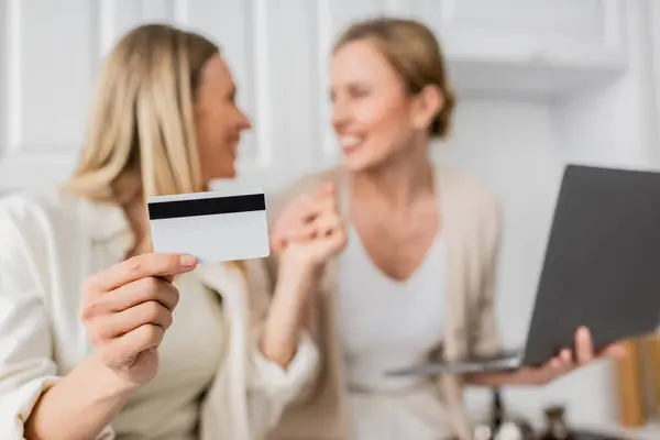 Close up two pretty trendy sisters in pastel outfit holding credit card, blurred, family bonding — Stock Photo