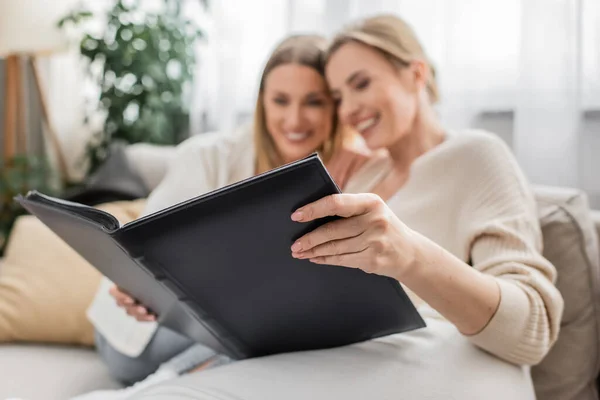 Close up lovely attractive sisters sitting on sofa and looking at photo album, family bonding — Stock Photo