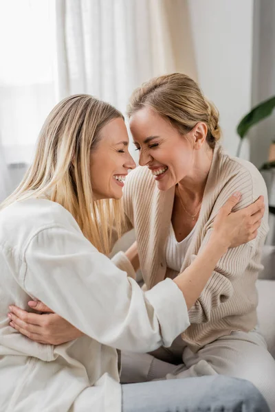 Close up two beautiful cheerful sisters hugging on sofa with closed eyes, togetherness, bonding — Stock Photo