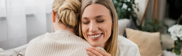 Hermosas hermanas bonitas con atuendo casual abrazándose y sonriendo sinceramente, vinculación familiar, pancarta - foto de stock